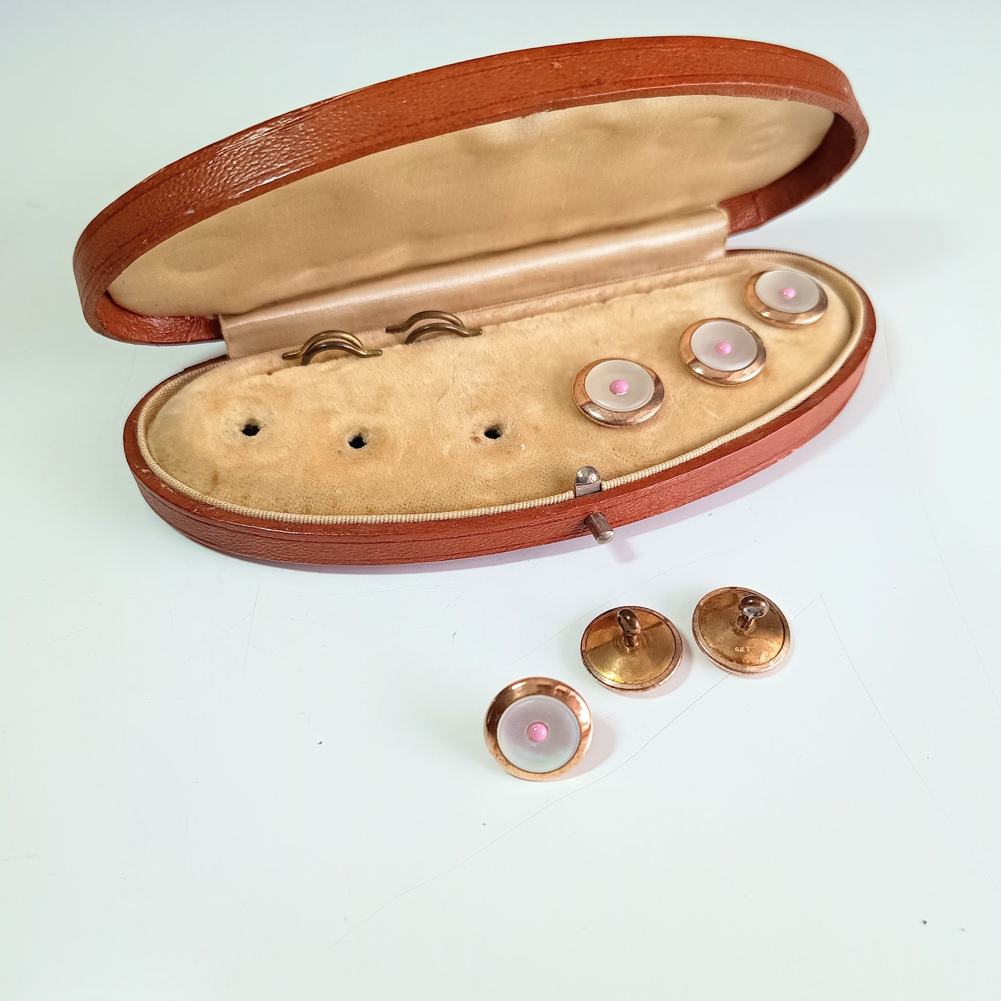 Open leather jewelry box with decorative buttons on a light background
