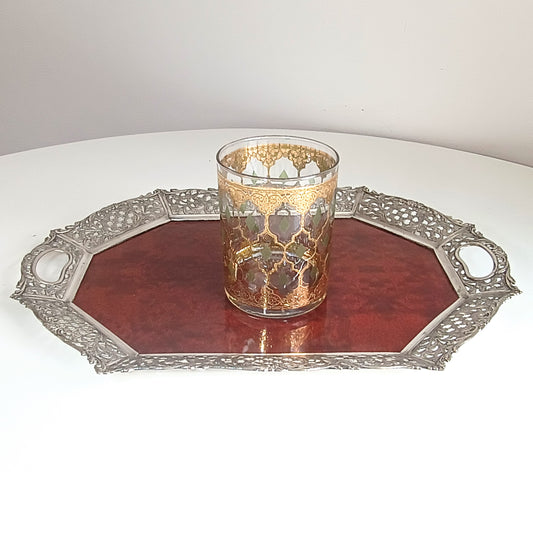 Decorative glass on a red tray with intricate silver border on a white background