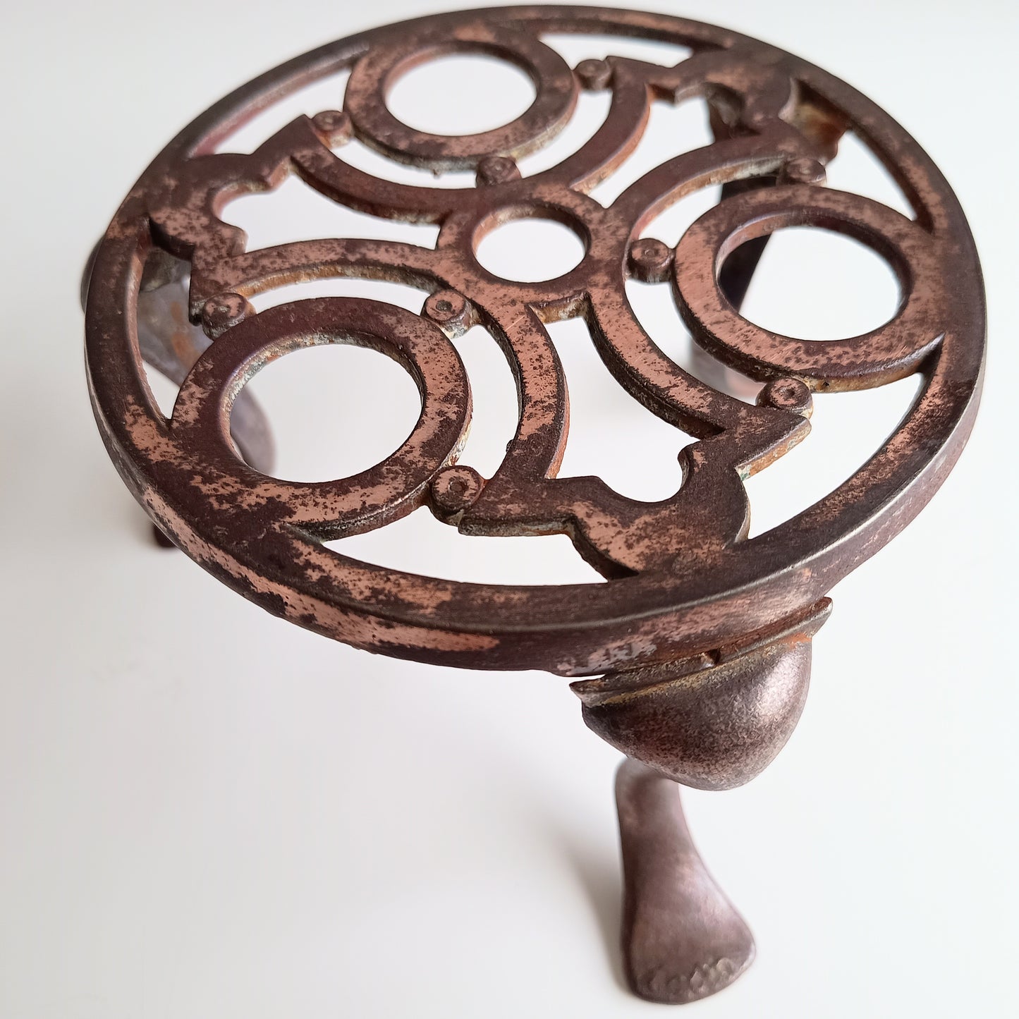 Decorative cast iron trivet with intricate design on a white background